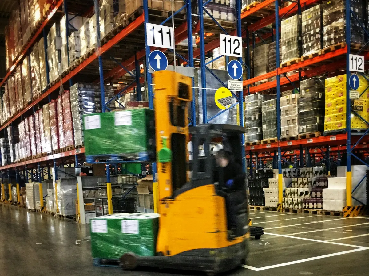 Reach truck working between pallet racks.